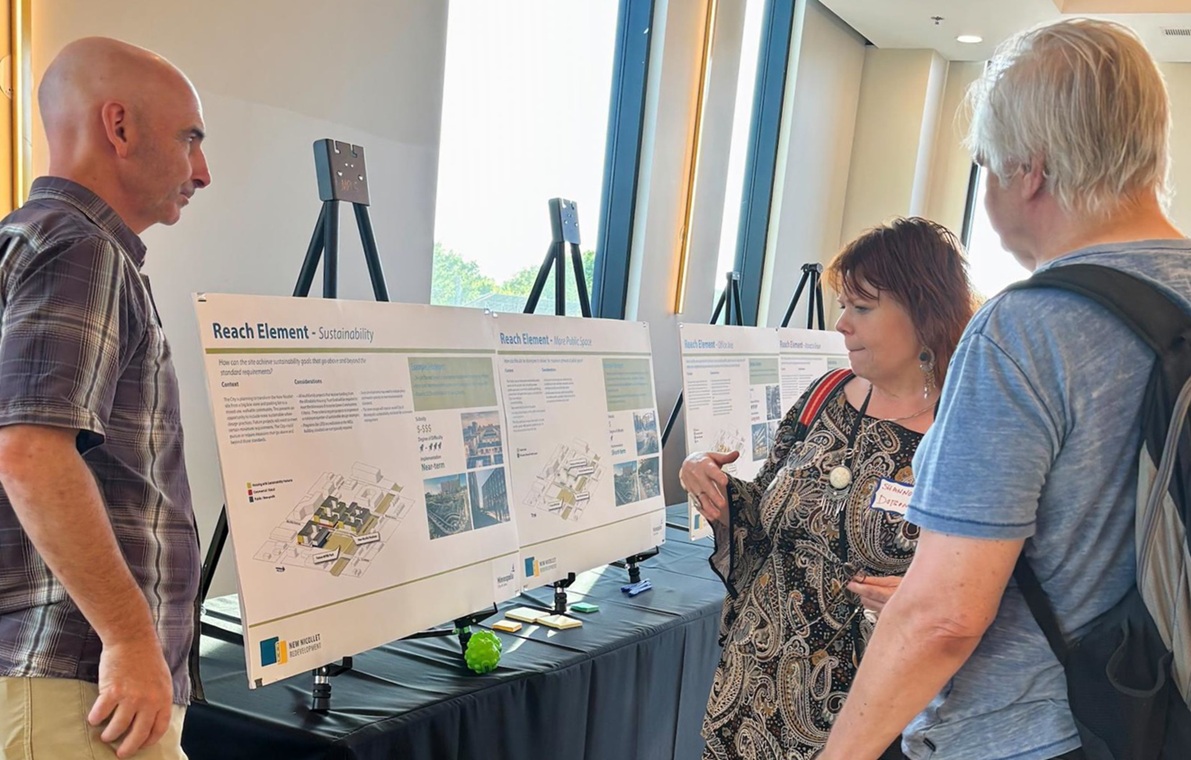 Three people looking at renderings displayed on easels