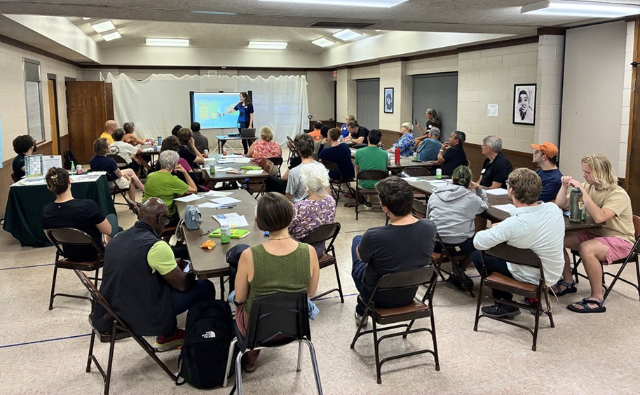 Group of people sitting in a room in front of a person pointing at a screen working on Phase 1 Development of New Nicollet