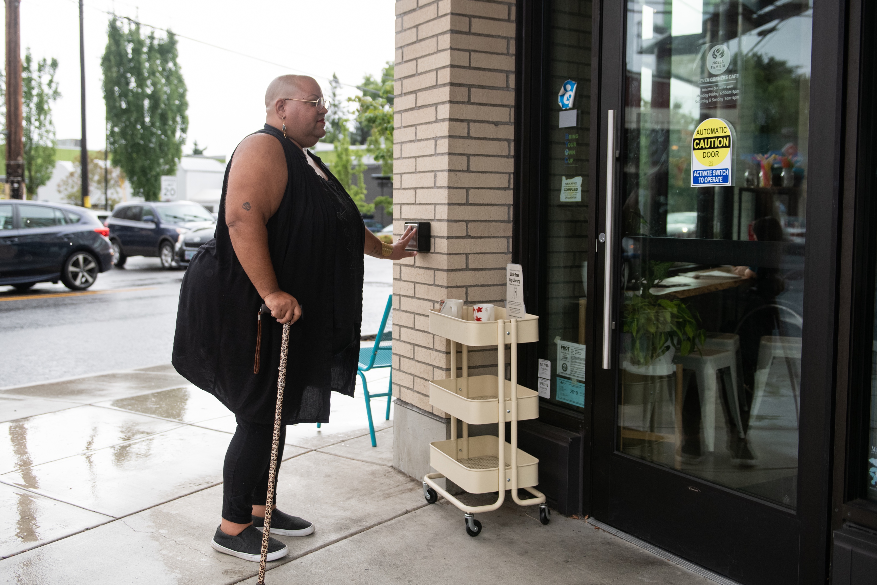 Person with disability with cane entering building. Credit: Disabled and Here