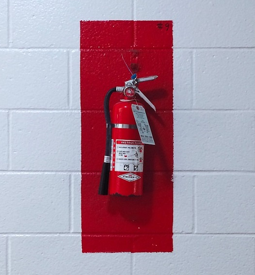 fire extinguisher on a white brick wall