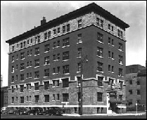 Sepia exterior photo of six story brick hotel in 1950.