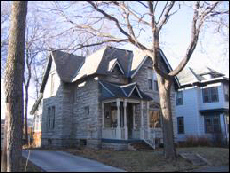 Color exterior photo taken from angle to show the side and front of the limestone home.