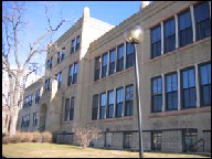 Faded closeup color photo of a two-story building with banks of vertical windows.