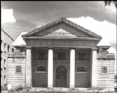 Sepia exterior photo looking directly at the church's front portico with two columns and gabled roof.