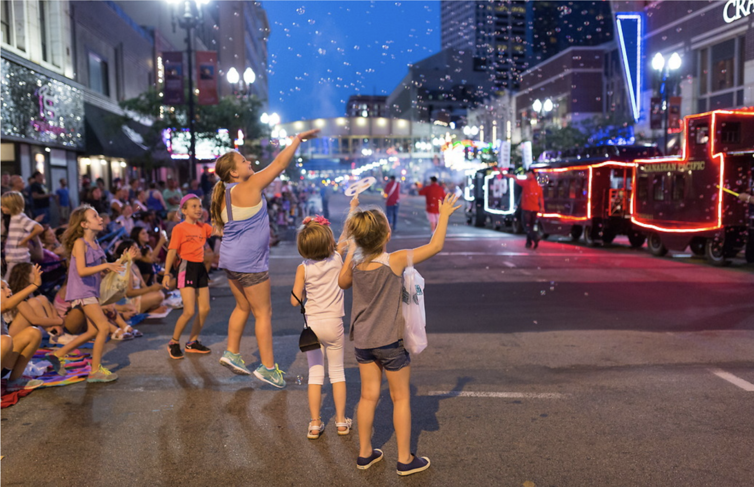 Kids watching a parade at night on a city street