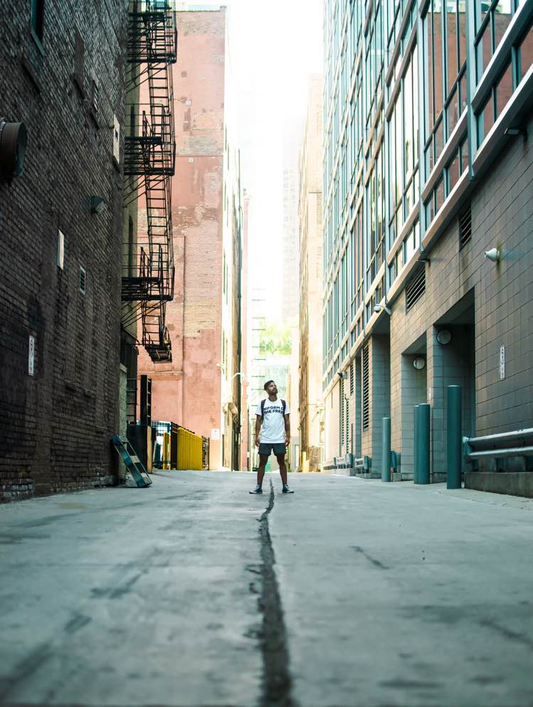 a man standing in an alley between tall buildings